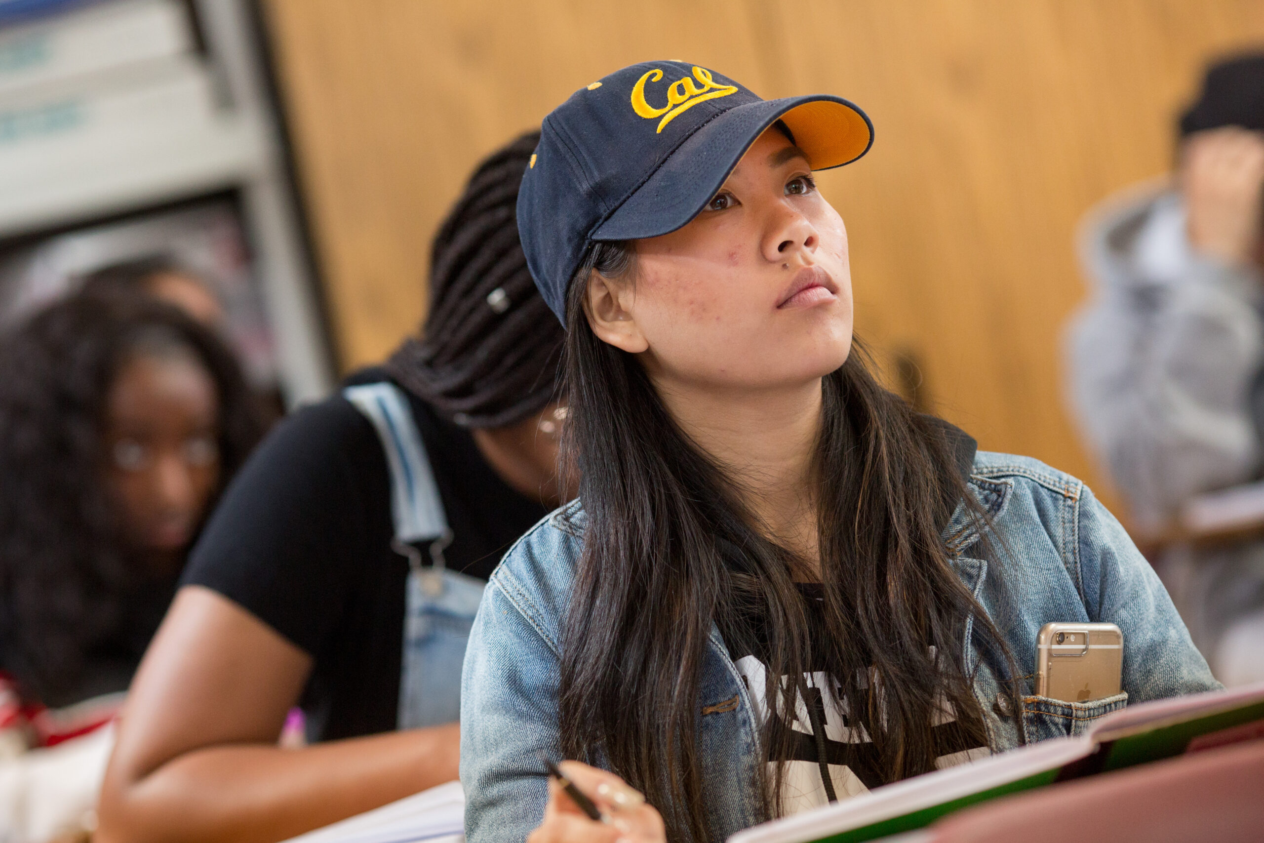 An image of a student listening to a presentation by her classmate.