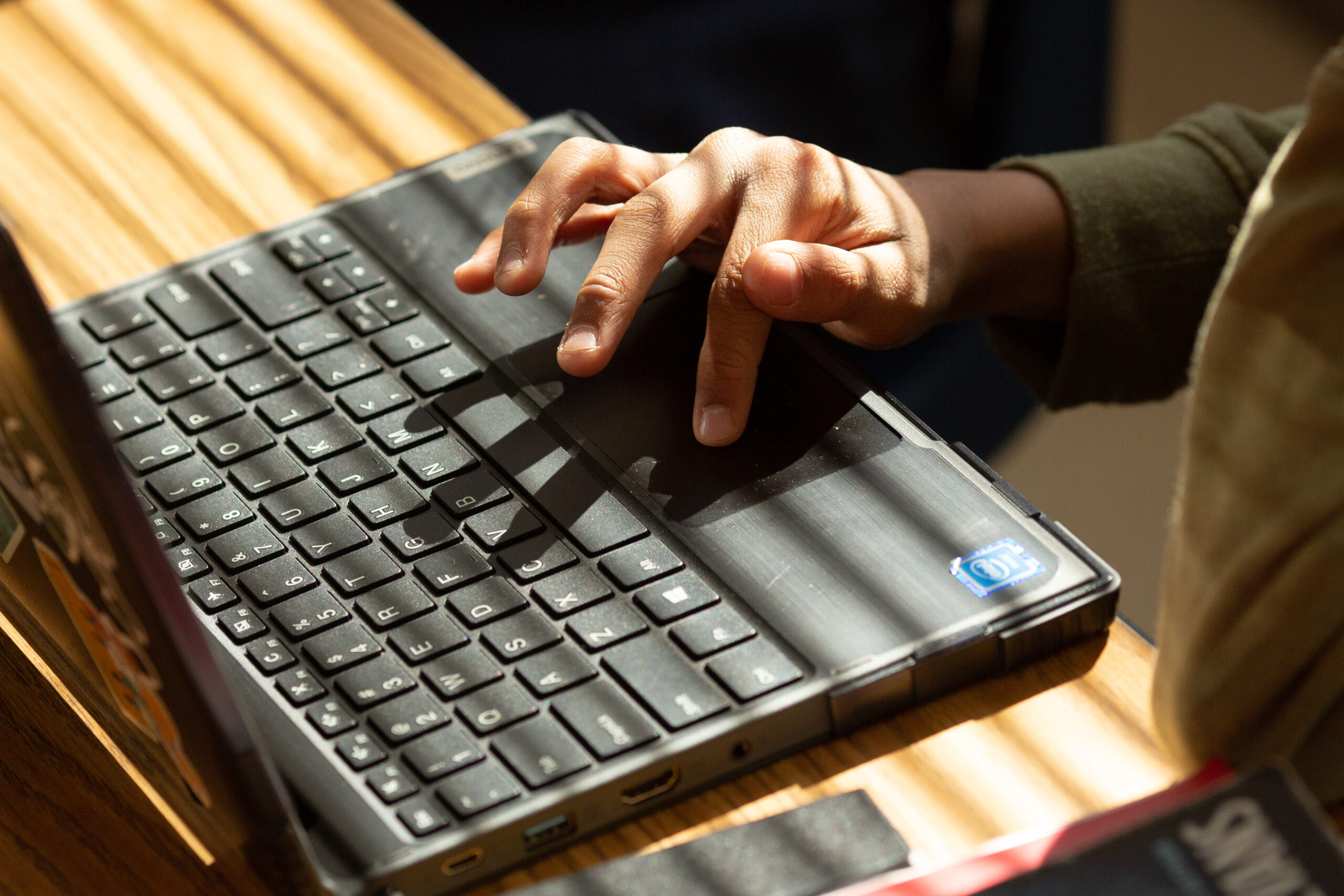 An image of a black computer and a students hand typing notes