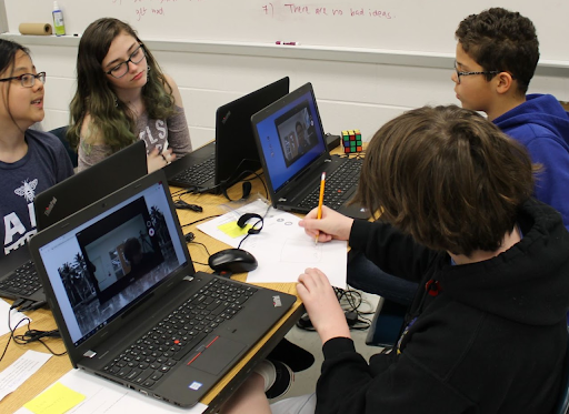 A group of students sitting around a table, while on their computers